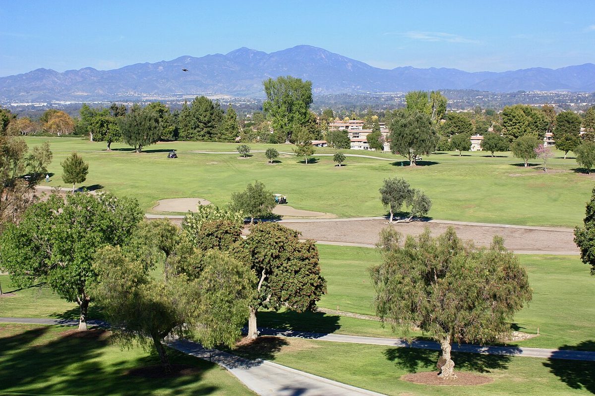 Golf course fairways and trees in Laguna Woods, California, with the Santa Ana Mountains in the distance