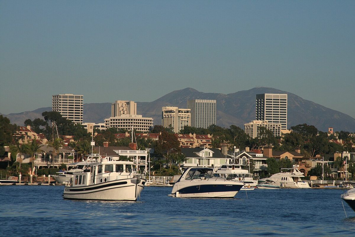 Newport Center office towers and the Santa Ana Mountains above boats in Newport Harbor, Orange County, California